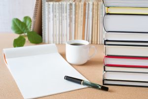 Blank sheet of paper on table with books and cup of coffee