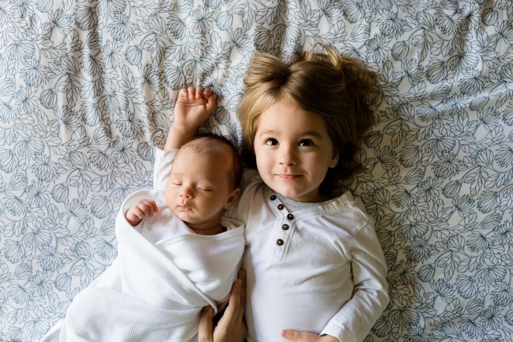 Work with early years. Baby and toddler lying on a bed.