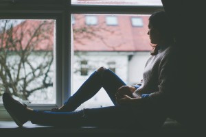 Symptoms of anxiety. Girl sitting by a window.