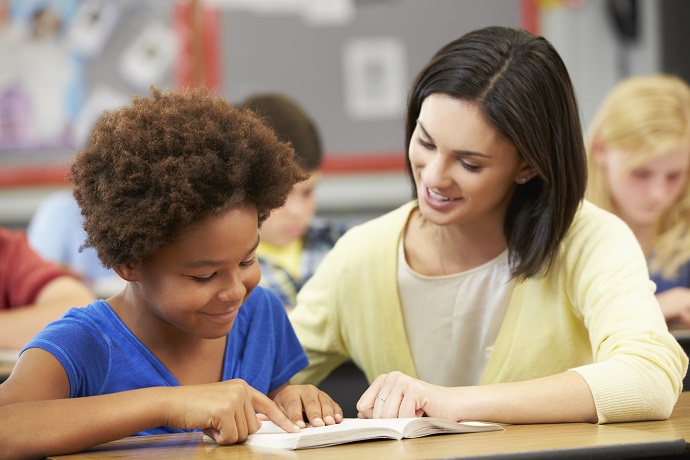 Woman using reading strategies to help a pupil.