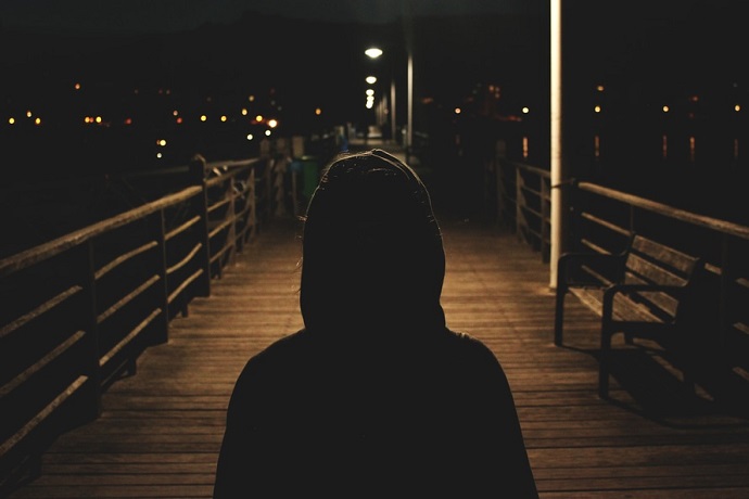 Psychology and criminology. Hooded man walking on a bridge