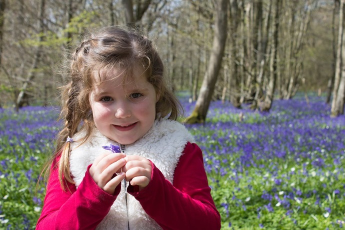 A girl picks flowers on a day out with a professional who has the qualifications to work with autistic children