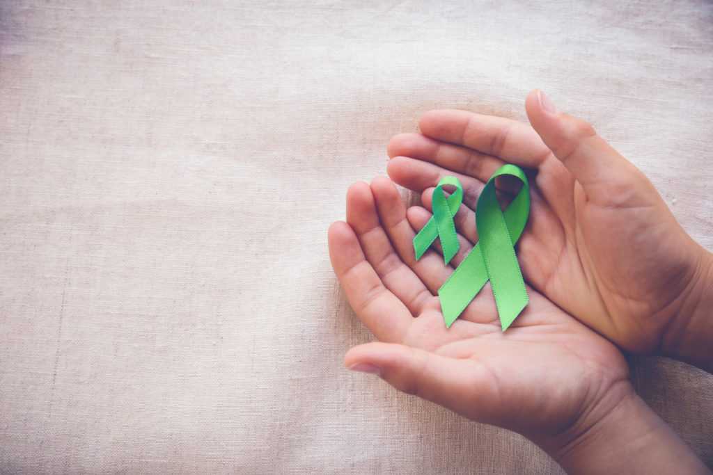 Hands holding a mental health awareness ribbon