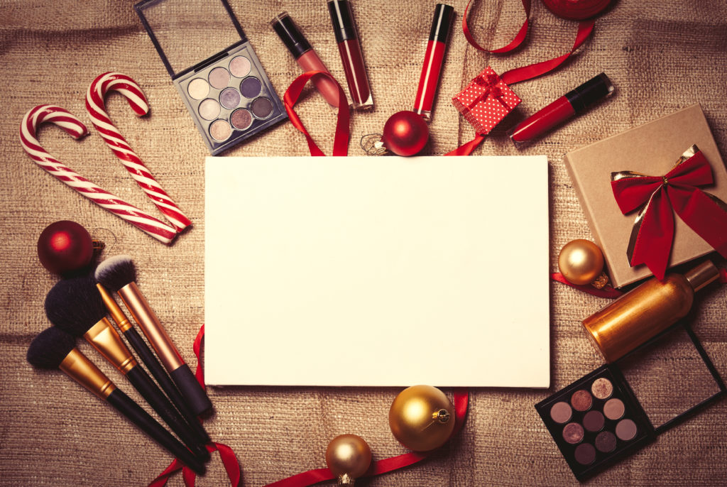 Cosmetics and Christmas gifts on jute background