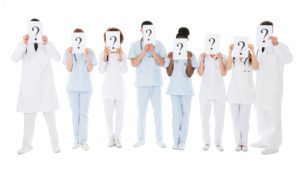 Group Of Multiracial Doctors Hiding Behind Question Mark Sign Over White Background