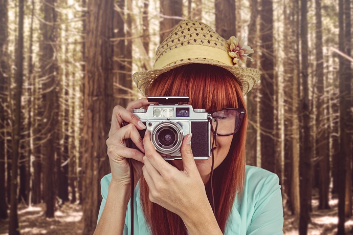 Portrait of a smiling hipster woman holding retro camera hobby