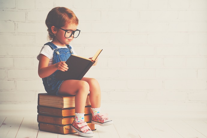 happy child little girl with glasses reading a books teachining assistant guided reading