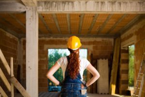 Confident Woman Bricklayer with Overalls and Helmet with Her Hands on Hips