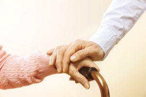 Senior elderly woman holding quad walking cane with her male doctor caregiver at nursing home. Retired pensioner old lady & man helping her to get up with stick. Background, close up, copy space.